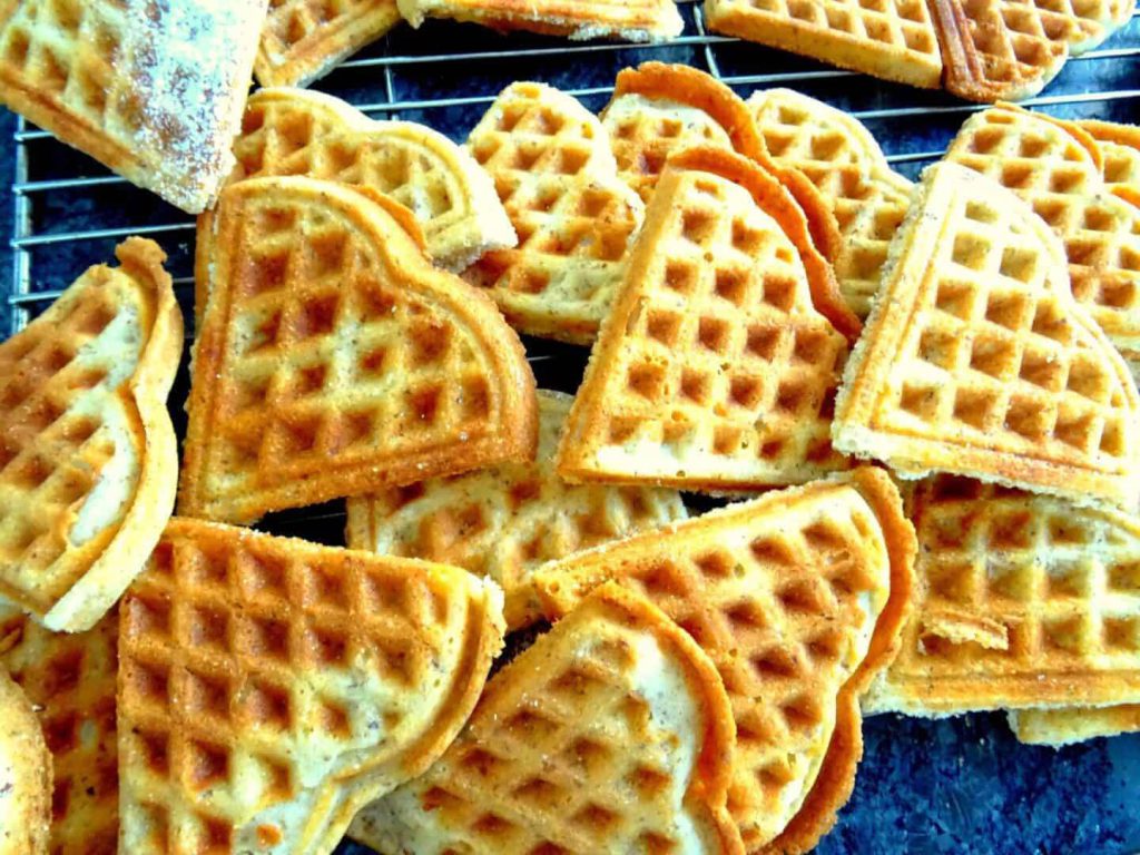 Dinkelwaffeln in Herzform, goldbraun gebacken, auf einem Kuchengitter angerichtet.