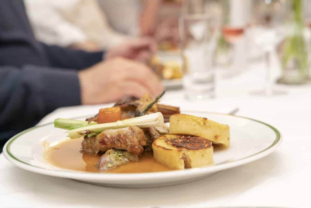 Zart gebratener Kitzschlögel mit Gemüse und Röstkartoffeln auf einem eleganten Teller.