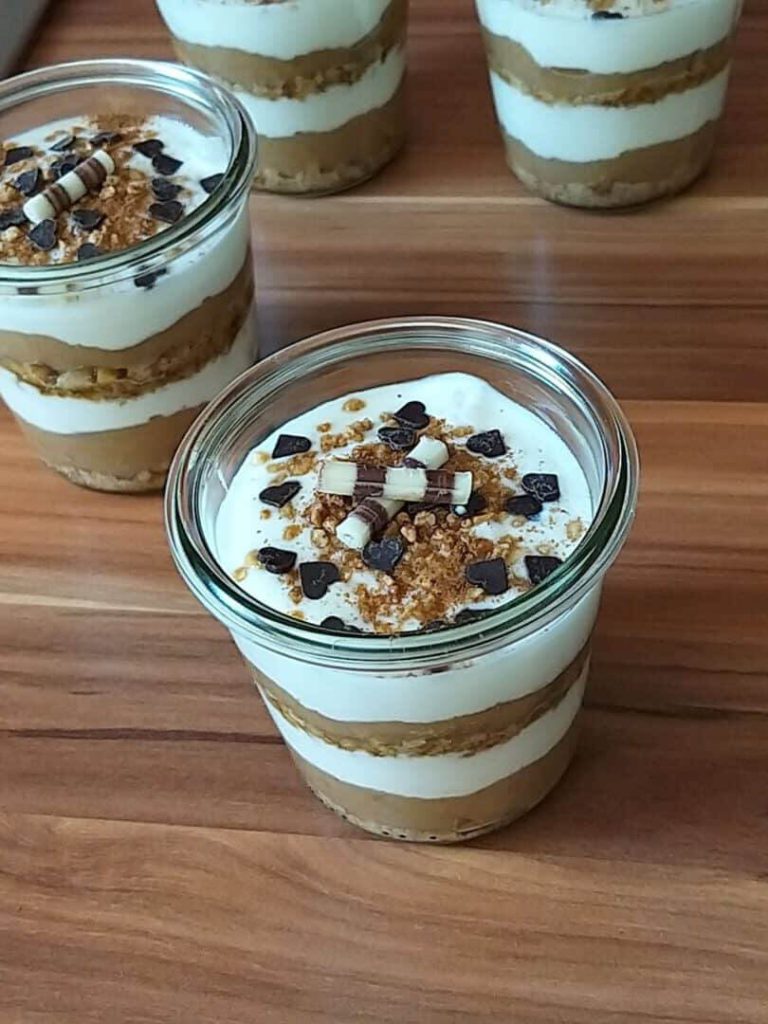 Apfelmus-Joghurt-Dessert in einem Glas mit Nüssen und Schokoladenstückchen dekoriert.