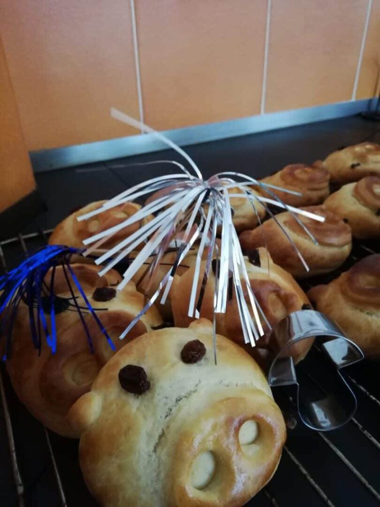 Glücksschweinderl aus Teig mit Dekoration, frisch gebacken auf einem Gitter.