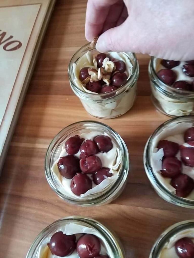 Mini-Kirsch-Topfenstrudel in Gläsern mit Kirschen und Nüssen garniert.
