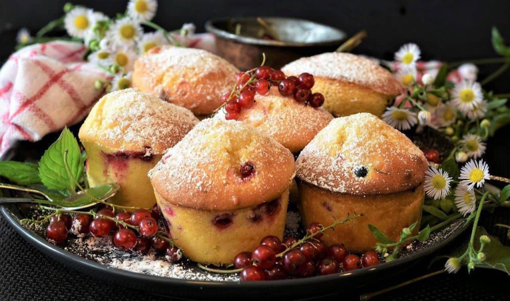 Saftige Obstkuchen mit Puderzucker und Beeren, dekoriert mit frischen Kräutern.