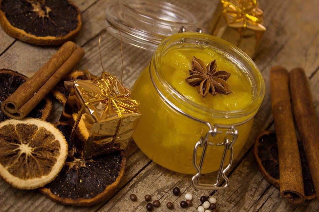 Glas mit Orangenmarmelade, dekoriert mit Sternanis, Zimt und Trockenfrüchten.