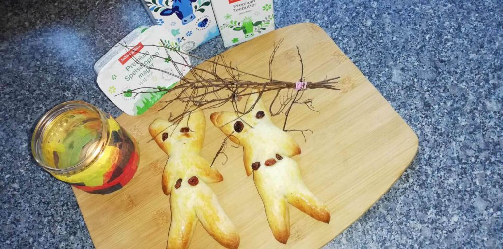 Zwei süße Krampusse aus Teig, garniert mit Zweigen und umringt von Zutaten.